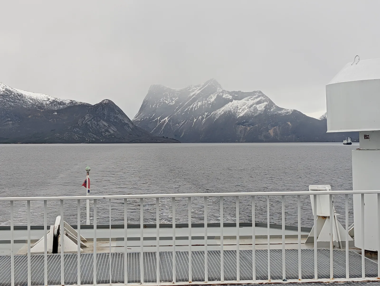From the open deck, a grey sky and, across the fjord, a line of jagged snow-covered peaks.